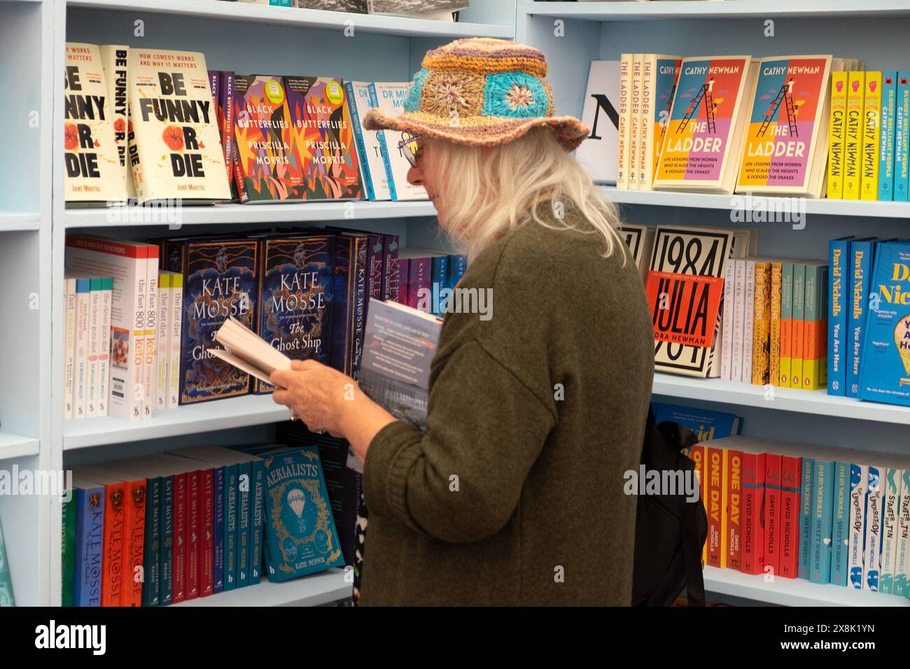 Person ältere Frau Strohhut Leserin liest Bücher zum Verkauf in Bücherregalen beim Hay Festival 2024 Hay-on-Wye UK KATHY DEWITT Stockfoto
