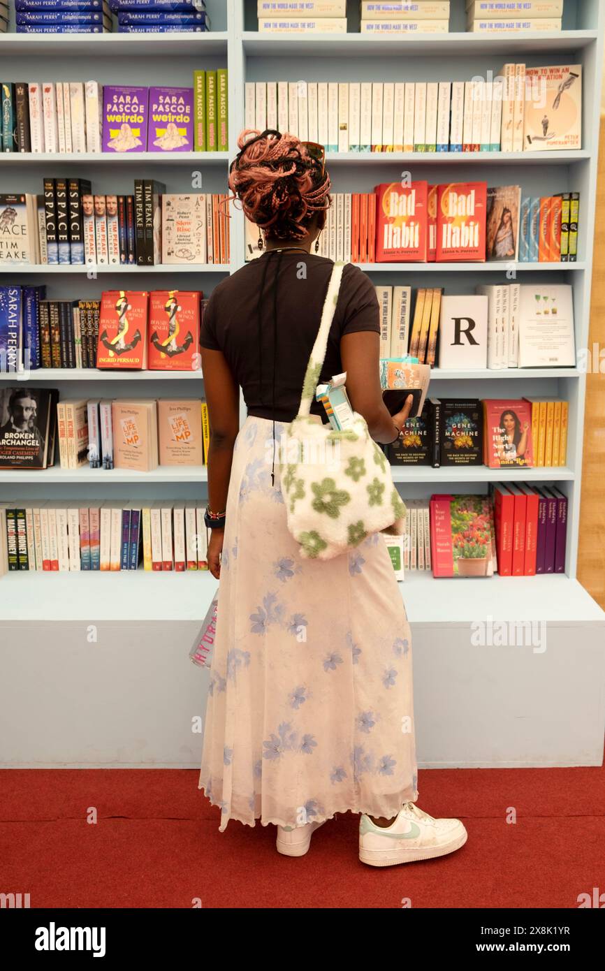 Person junge Frau, die nach hinten liest und Bücher zum Verkauf in Bücherregalen im Buchladen beim Hay Festival 2024 Hay-on-Wye UK ansieht, KATHY DEWITT Stockfoto