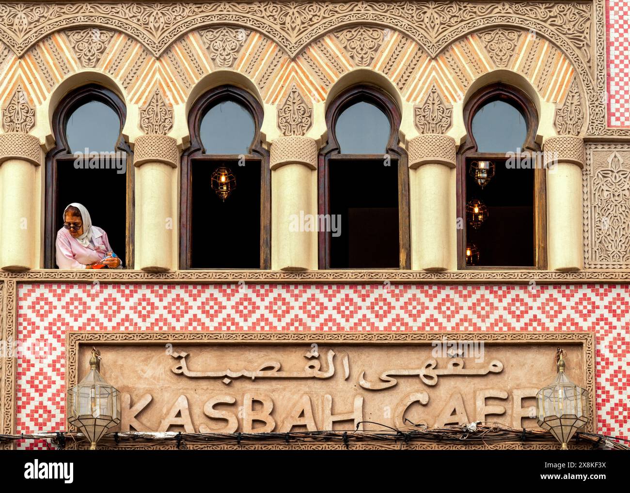 Marrakesch, Marokko - 23. März 2024: Muslimische Frau beobachtet das Leben der Stadt und blickt aus dem Fenster des Kasbah Café in der Innenstadt von Marrakesch Stockfoto
