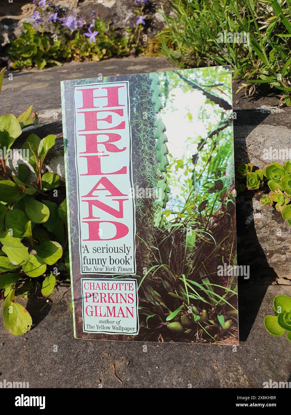 Herland Roman von Charlotte Perkins Gilman Buch in einer Gartenlandschaft Stockfoto