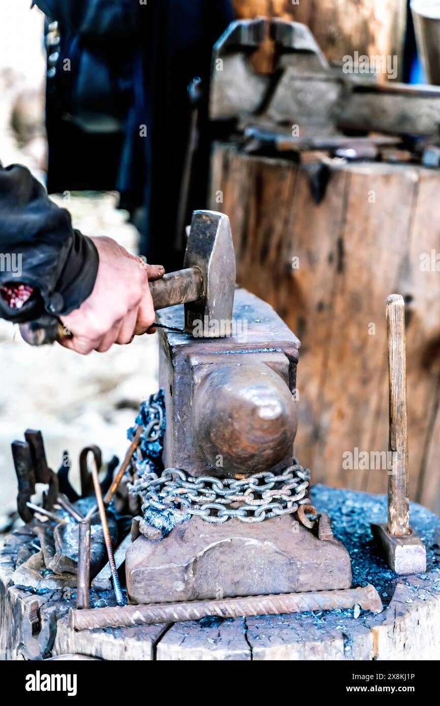 Ein Schmied in einer Schmiede arbeitet an einem Amboss. Heißmetallschmieden. Hochwertige Fotos Stockfoto