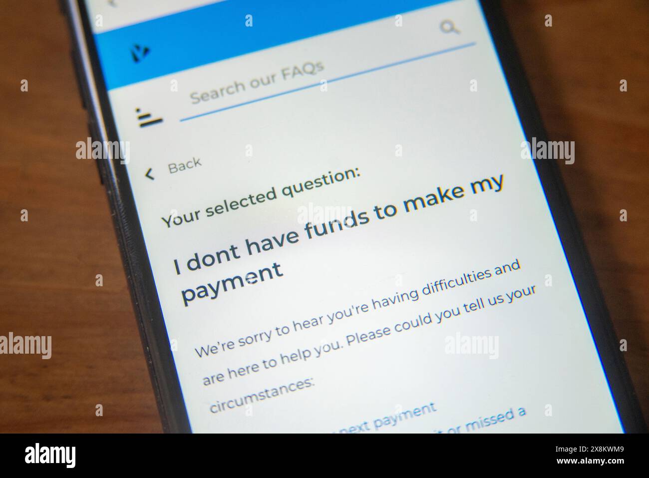Mobiltelefon-Bildschirm mit einer FAQ-Seite über unzureichende Zahlungsmittel, auf der finanzielle Schwierigkeiten und Unterstützungsoptionen hervorgehoben werden Stockfoto