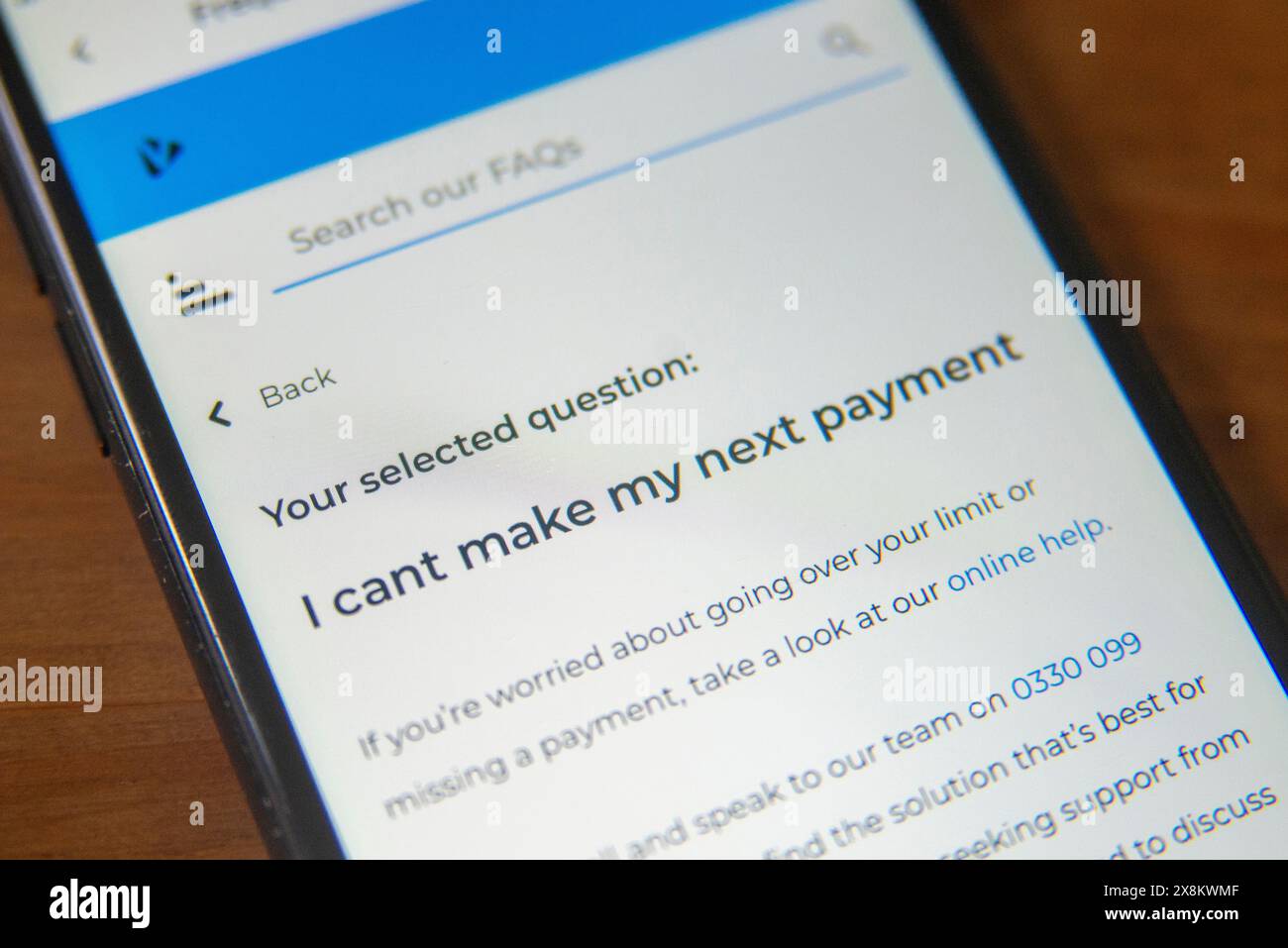 Mobiltelefon-Bildschirm mit einer FAQ-Seite über unzureichende Zahlungsmittel, auf der finanzielle Schwierigkeiten und Unterstützungsoptionen hervorgehoben werden Stockfoto