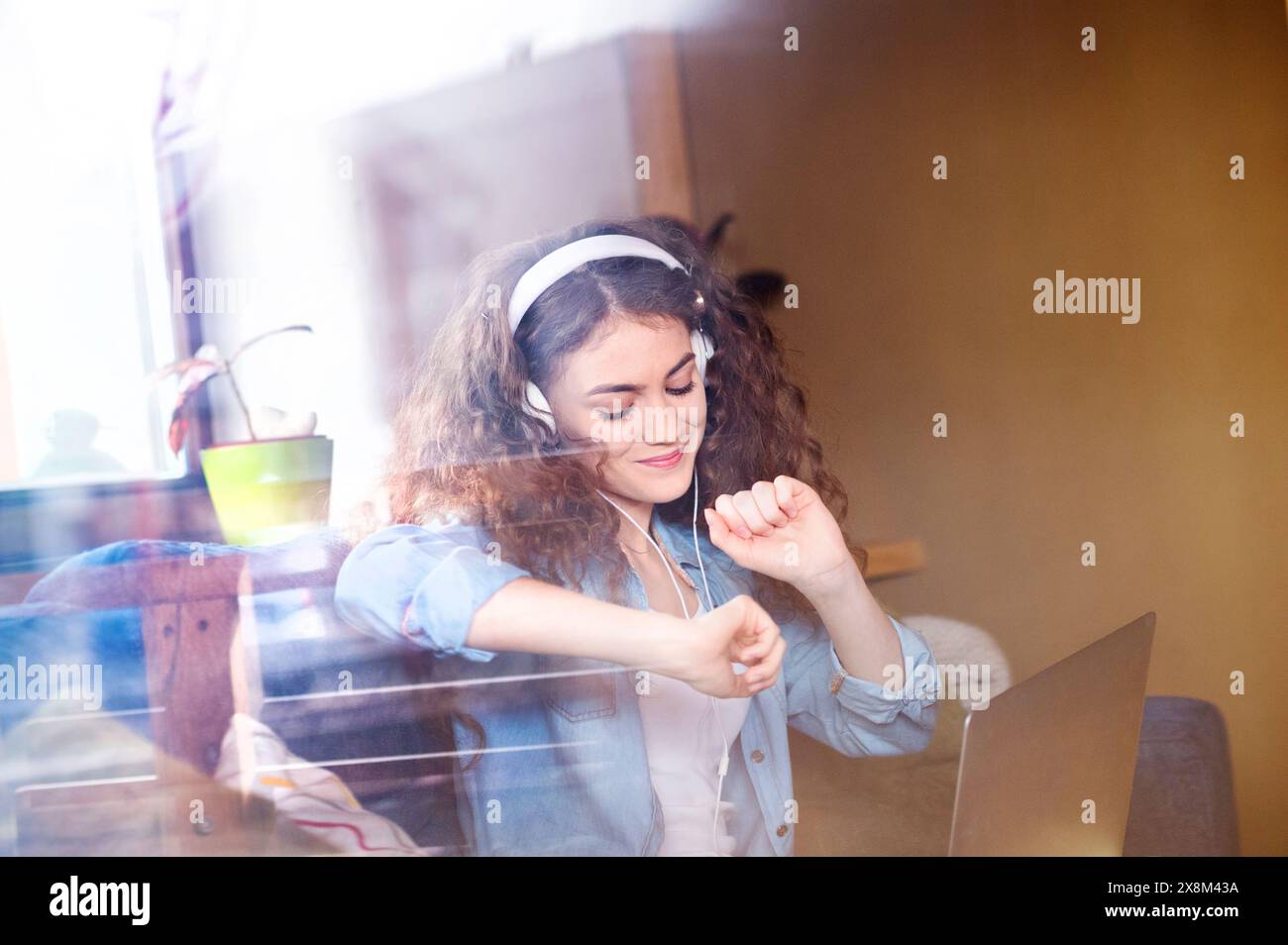 Schöne Frau mit lockigem Haar, die Kopfhörer trägt, Musik hört, positive Affirmationen. Stockfoto