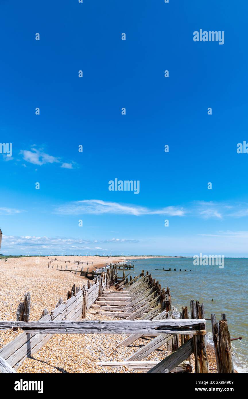 Großer, tiefblauer Himmel über der Meeresschutzmauer im Rye Harbour Nature Reserve, England, mit einigen schimmernden weißen Wolken, Perspektive und Horizont. Stockfoto