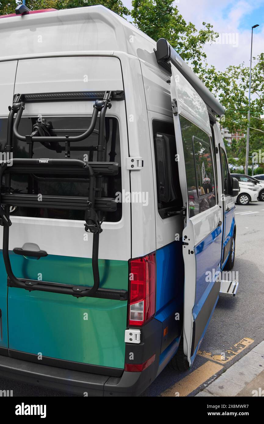 Weißer Van mit offener Seitentür mit blauen und grünen Streifen mit Fahrradständer und einziehbarer Markise, perfekt für Ausflüge im Freien. Stockfoto