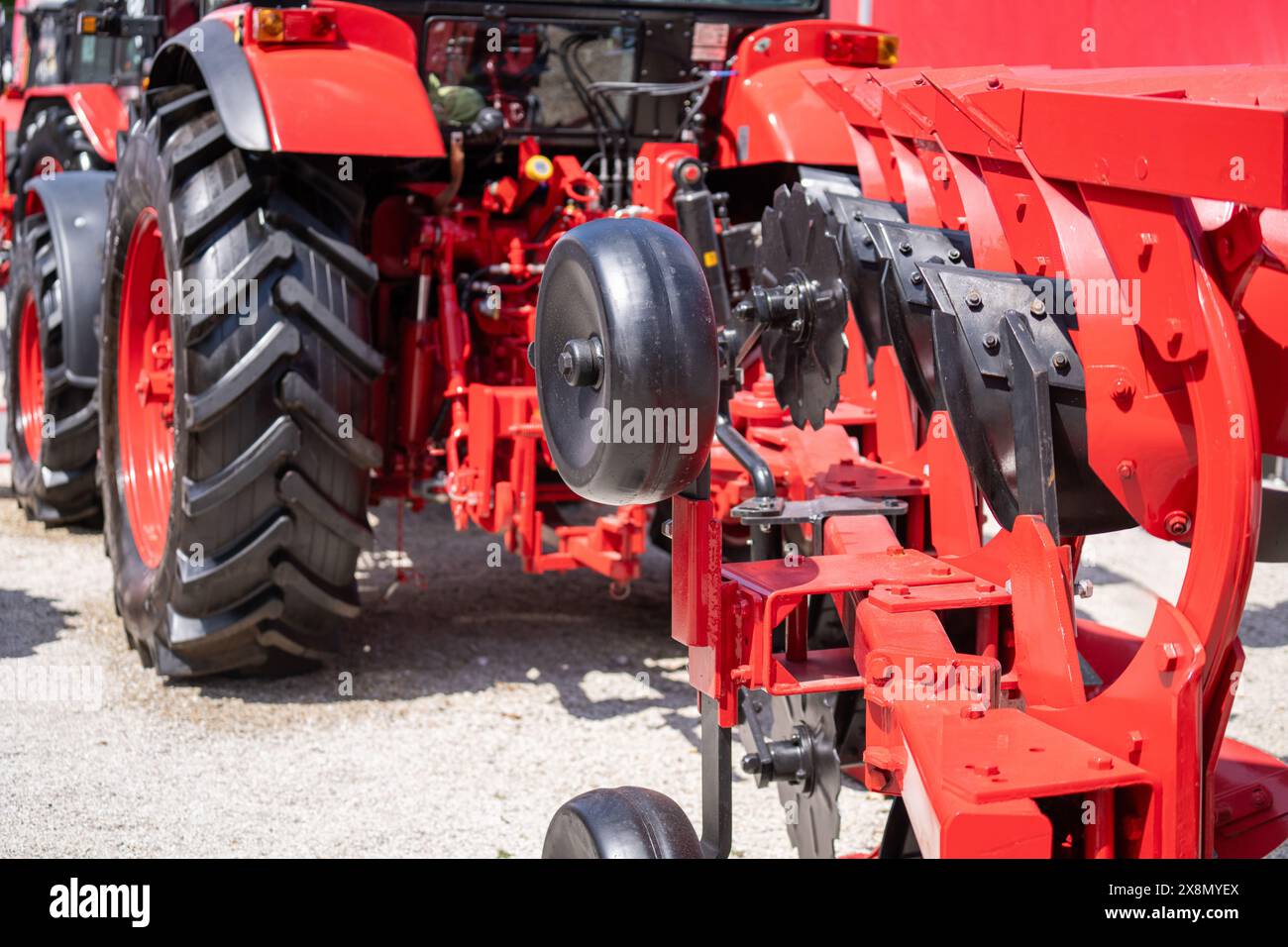 Roter Traktor mit Pflug auf einem landwirtschaftlichen Feld. Stockfoto