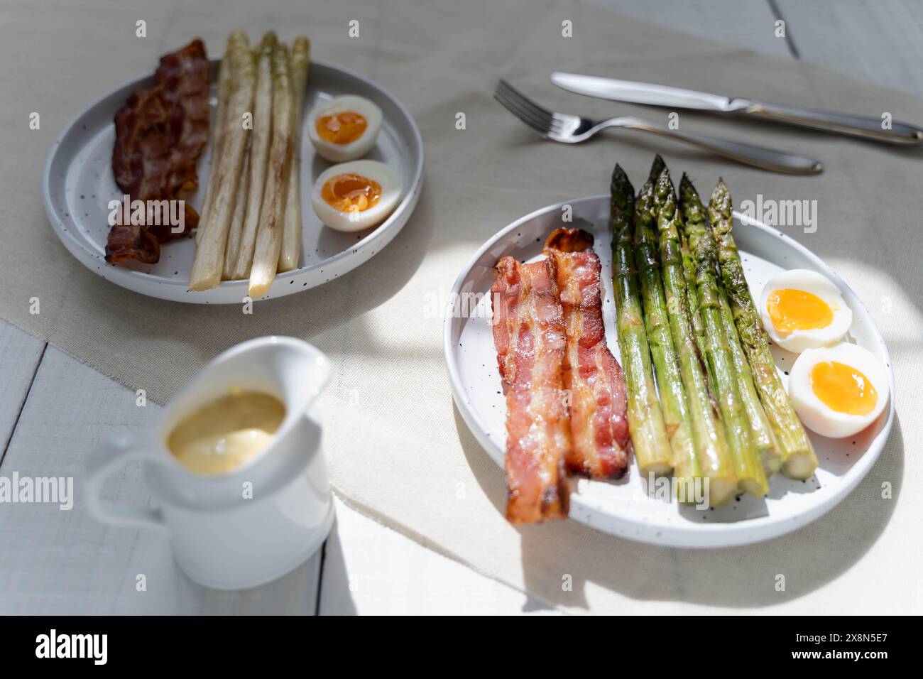 Grüner und weißer Spargel serviert mit gekochten Eiern und Speck. Spargel, der Ballaststoffe repräsentiert, ist in Deutschland während der Spargelzeit sehr beliebt Stockfoto