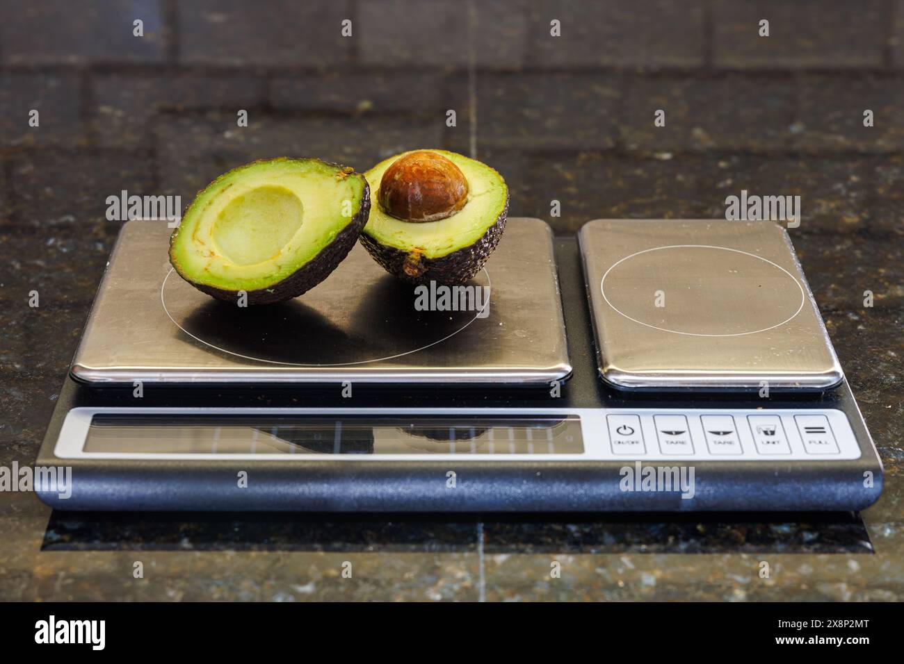 Avocadohälften auf Küchenwaage für Portionskontrolle und gesunde Essgewohnheiten Stockfoto