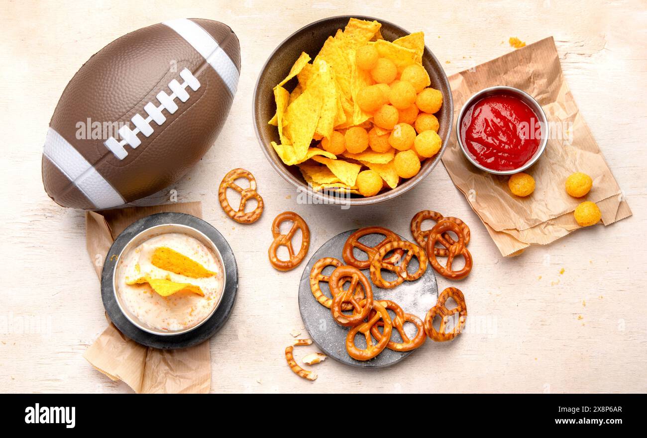 Snacks zum Anschauen eines American Football-Spiels. Bier, Chips, Brezeln, Soße auf hölzernem Hintergrund. Draufsicht Stockfoto