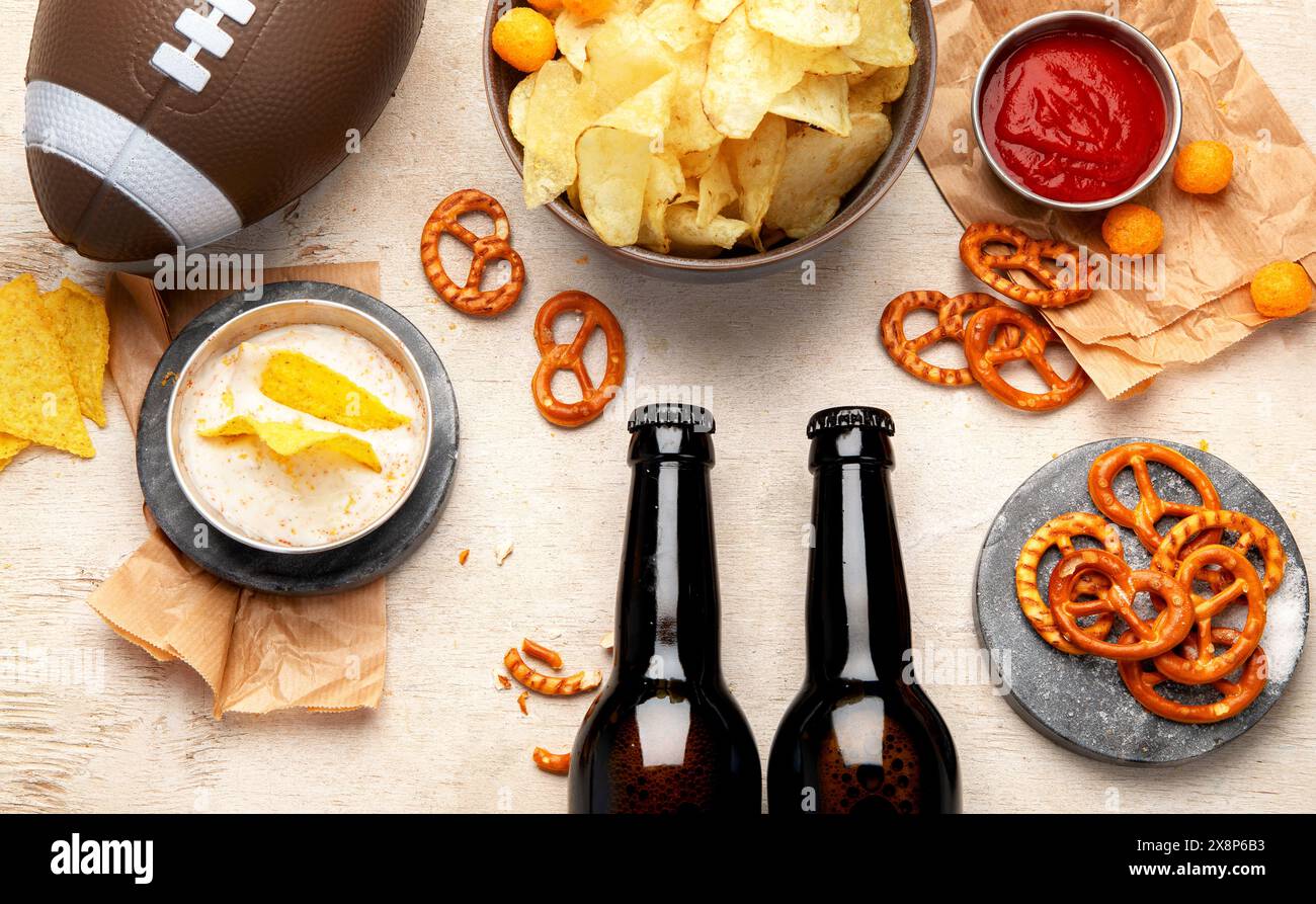 Snacks zum Anschauen eines American Football-Spiels. Bier, Chips, Brezeln, Soße auf hölzernem Hintergrund. Draufsicht Stockfoto