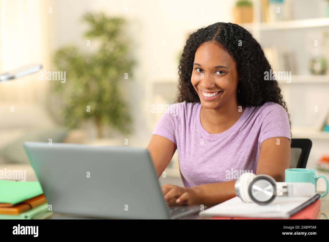 Glücklicher schwarzer Schüler, der sich zu Hause das E-Learning mit der Kamera anschaut Stockfoto