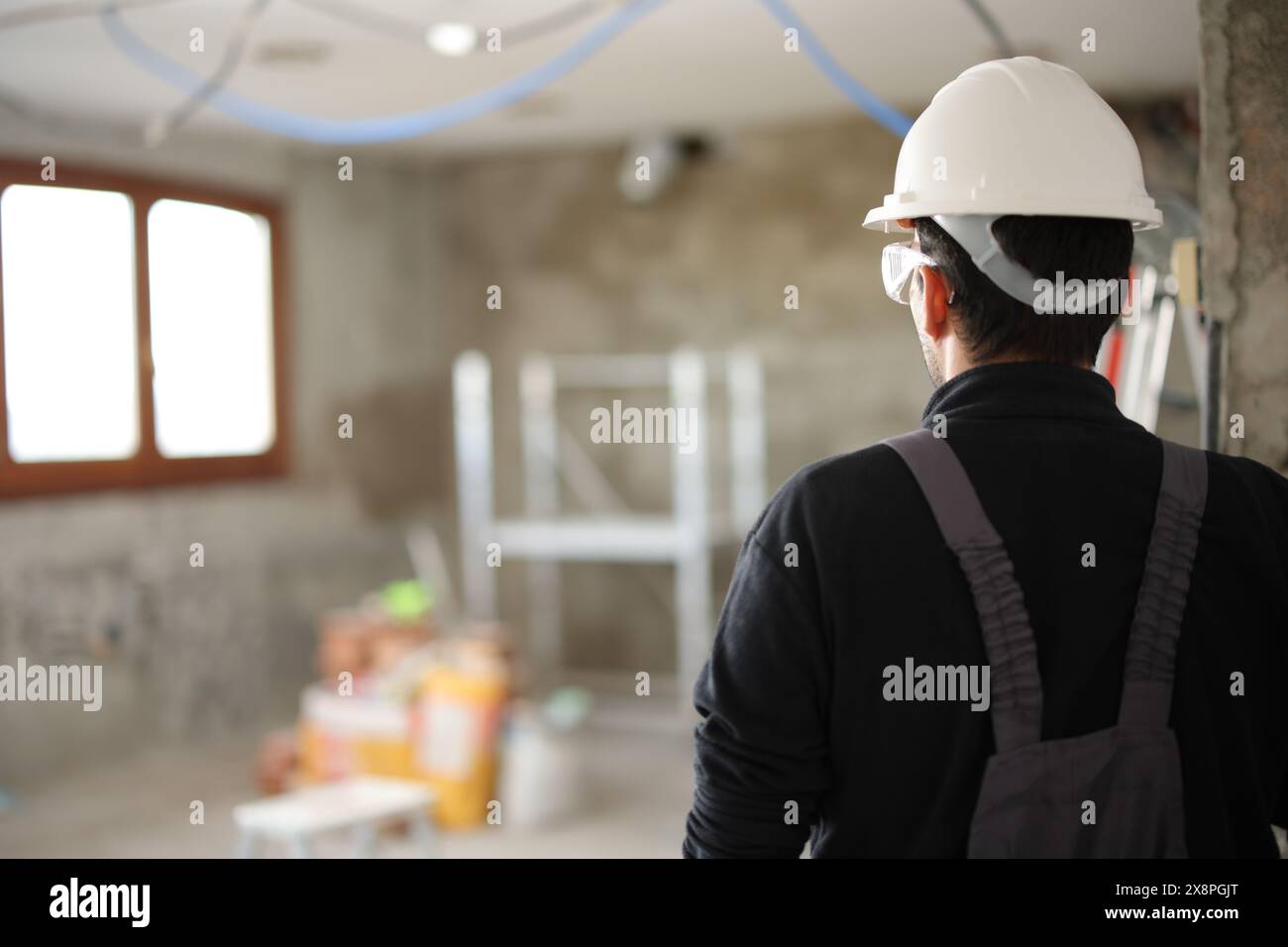 Rückansicht Porträt eines Bauarbeiters, der auf die gerade renovierte Baustelle blickt Stockfoto