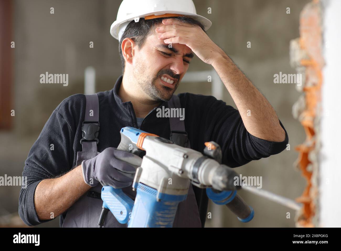 Bauarbeiter leiden unter Kopfschmerzen nach Arbeiten mit lautem Bohrhammer Stockfoto