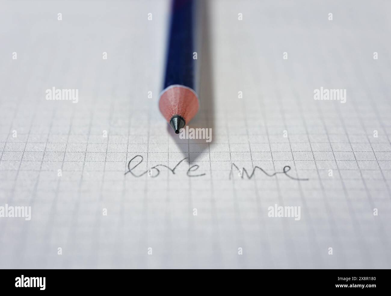 Blatt weißes Papier mit handgeschriebenen Worten LIEBE MICH mit Bleistift, Paarbeziehung Stockfoto