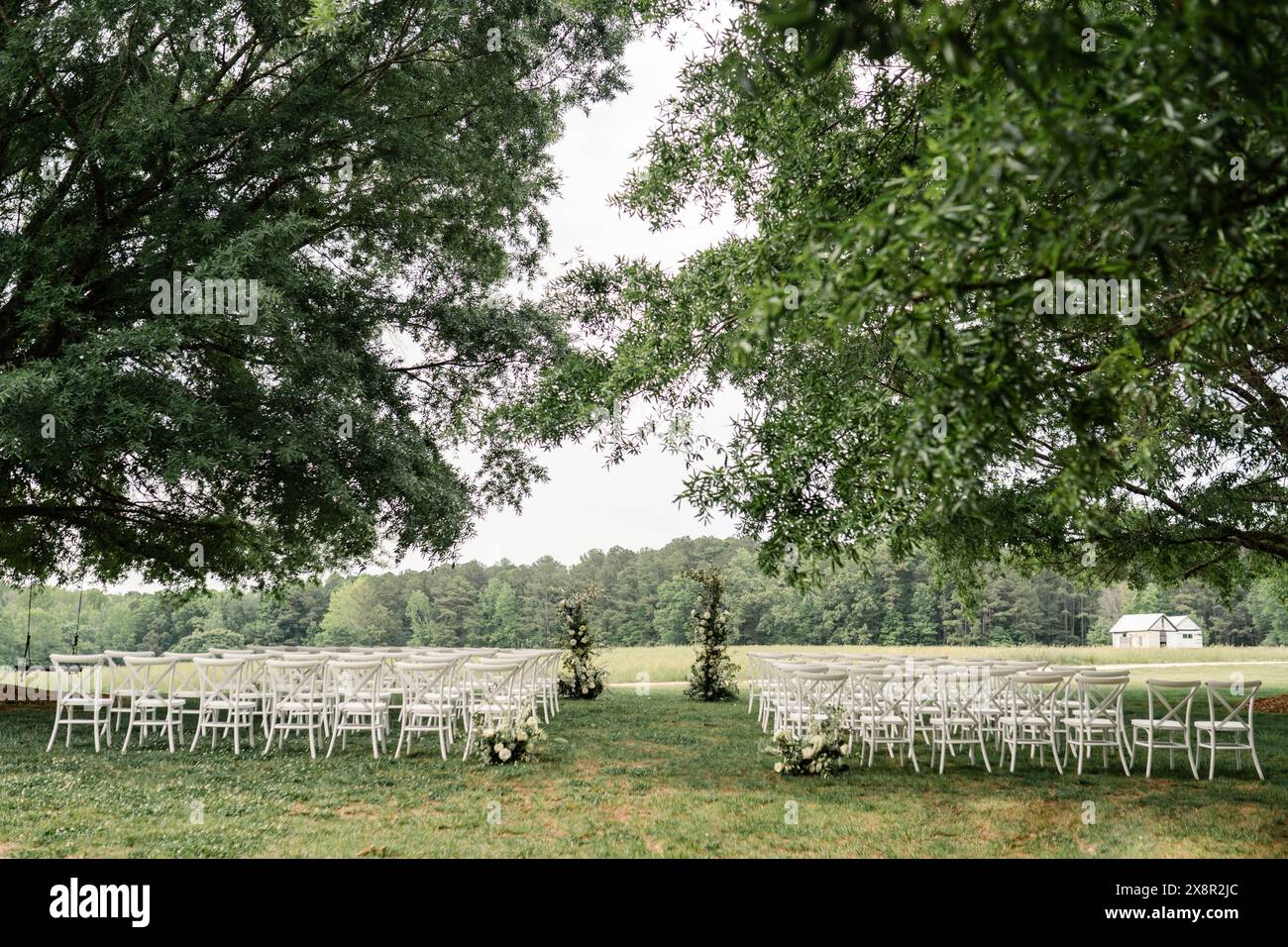 Hochzeitszeremonie im Freien mit weißen Stühlen und Blumen Stockfoto