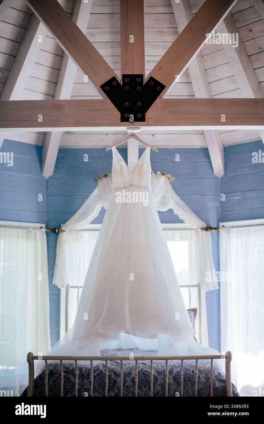 Hochzeitskleid hängt im rustikalen blauen Loft mit Balken Stockfoto