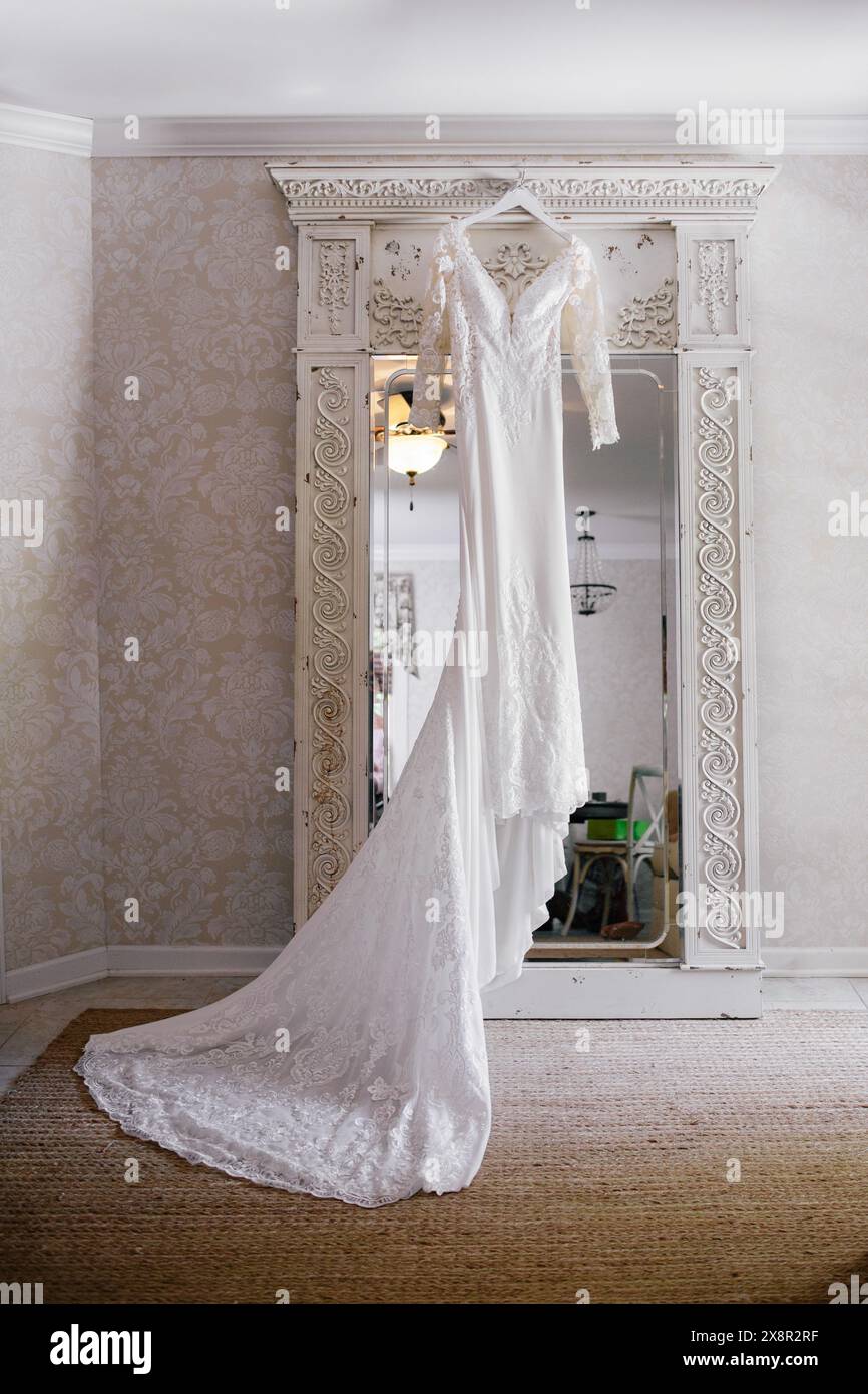 Elegantes Hochzeitskleid mit Spitze, das am kunstvollen Spiegel hängt Stockfoto
