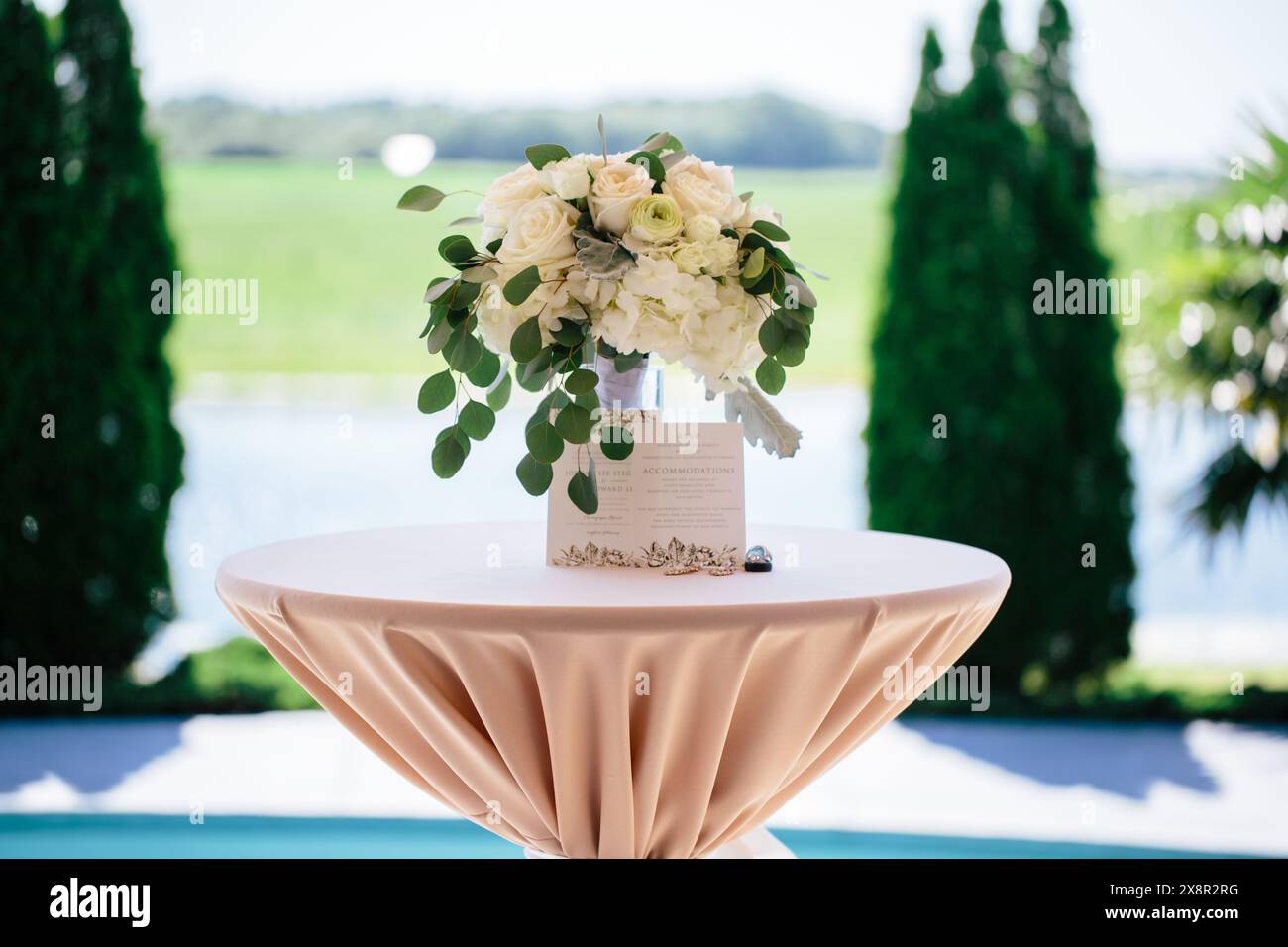 Elegante Blumenarrangements und Hochzeitseinladungen am Seeufer Stockfoto