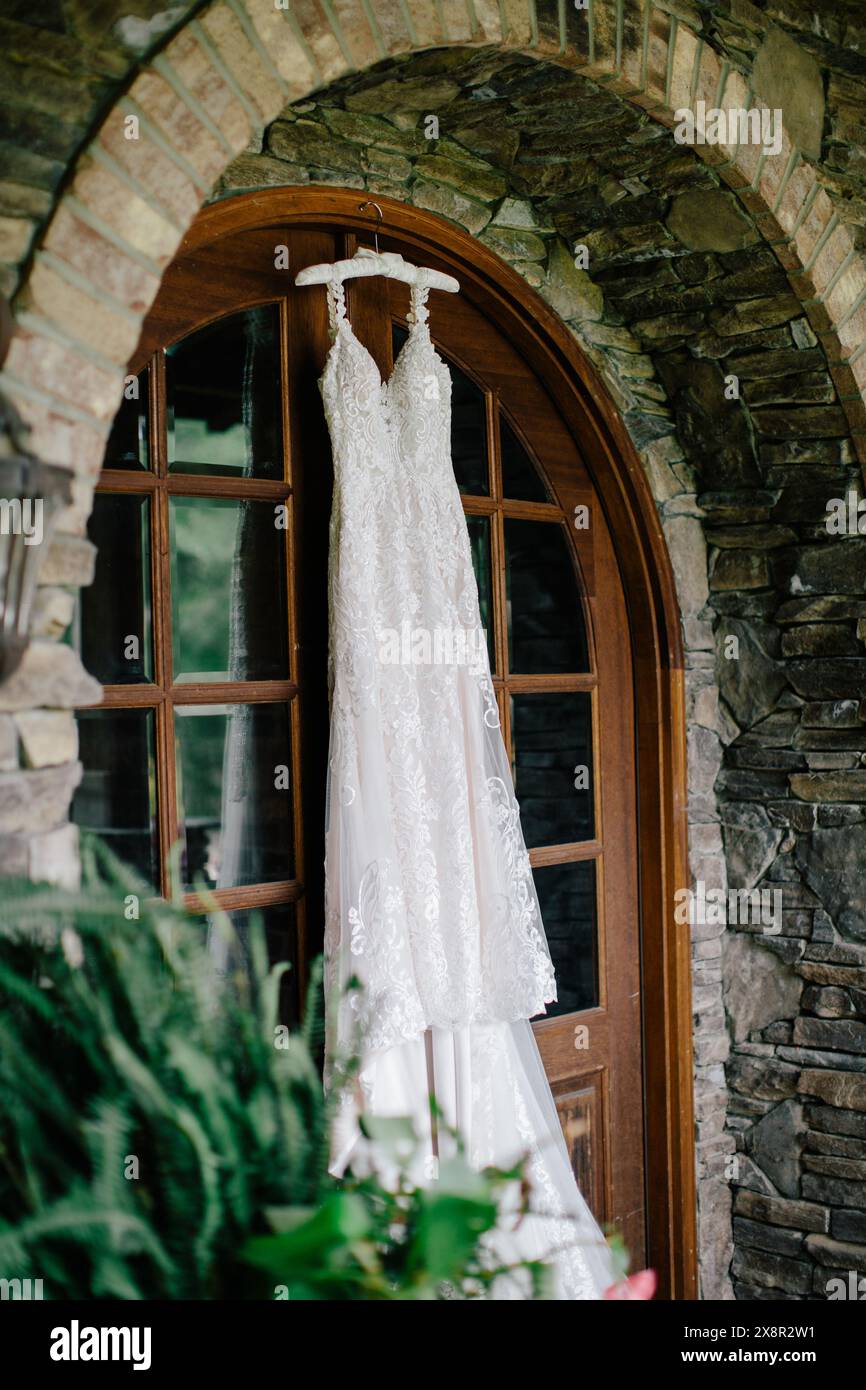 Elegantes Hochzeitskleid aus Spitze, das in einem rustikalen Steinbogen hängt Stockfoto