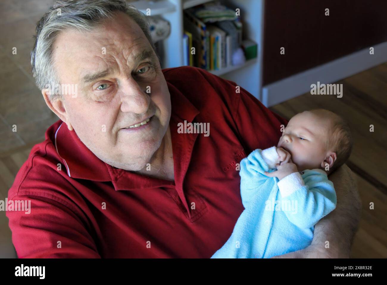 Der stolze Großvater hält das Neugeborene liebevoll und teilt einen zarten Moment Stockfoto