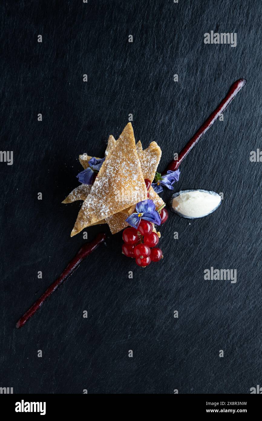 Kunstvoll überzogenes Dessert mit essbaren Blumen und Obstgarnitur Stockfoto