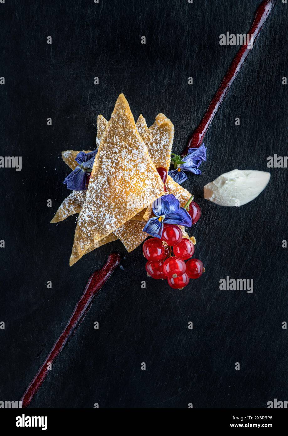 Kunstvoll überzogenes Dessert mit essbaren Blumen und Obstgarnitur Stockfoto