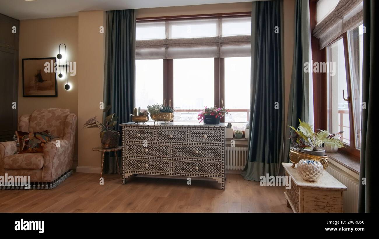 Gemütliches Interieur eines neuen Apartments in Beige- und Brauntönen. Kreativ. Sessel und Schublade am Fenster. Stockfoto