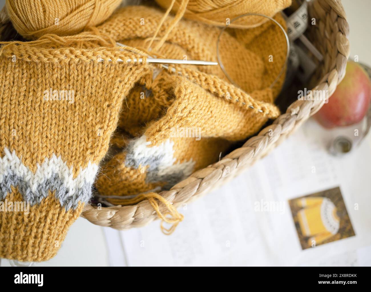 Gelber Strickpullover aus isländischer Wolle für Kinder in Progress mit Garnbällchen, Nadeln und Muster Stockfoto