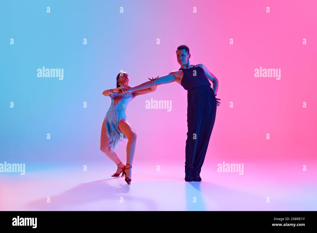 Tänzer im Ballsaal, Mann und Frau in Modekostümen der Bühne posieren in Neonlicht vor verlaufendem Hintergrund. Stockfoto
