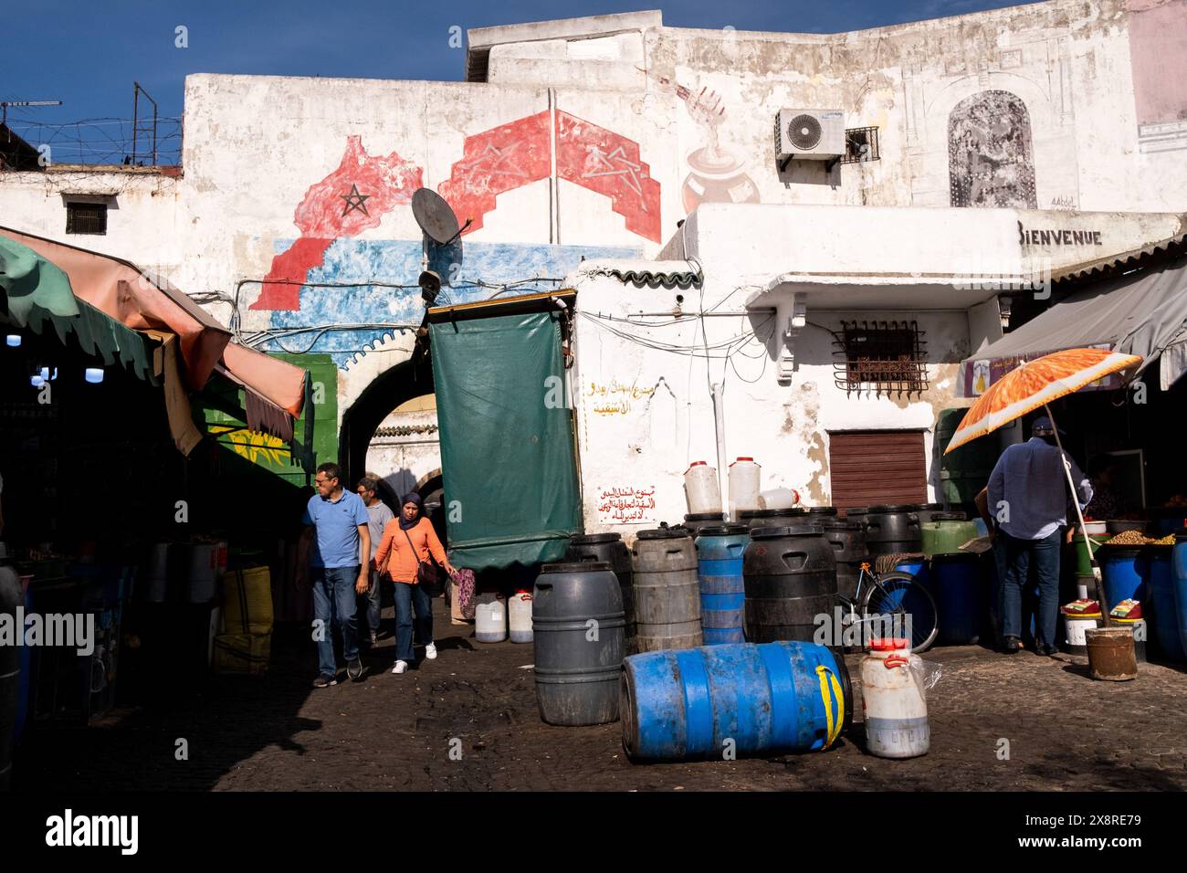 Menschen, die am 7. Oktober 2023 in der Nähe einer Mauer mit einem gemalten Wandbild der marokkanischen Karte und Flagge im Habous-Viertel Casablanca, Marokko, spazieren. Dieses AR Stockfoto