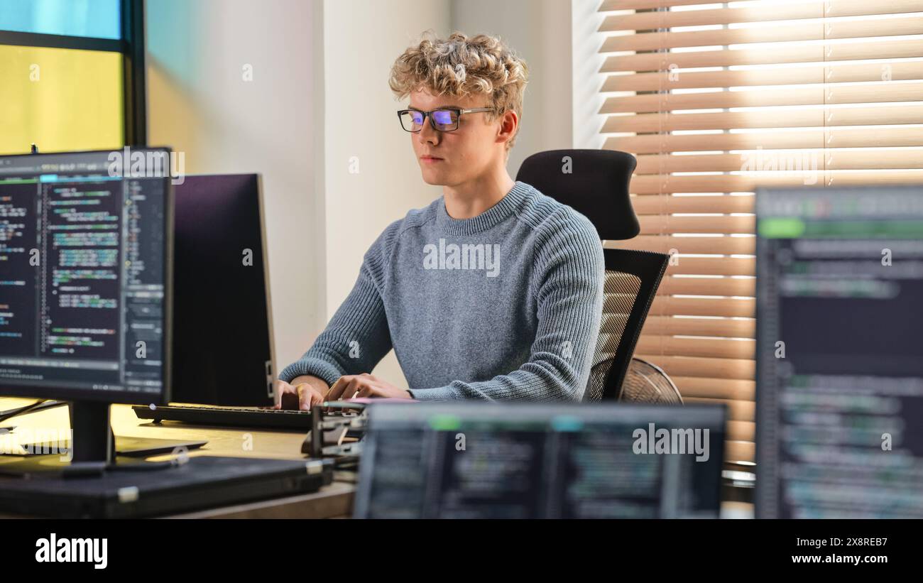 Codierung des männlichen Software Engineers auf Desktop-Computern im kreativen Bürobereich. Junger kaukasischer Mann, der seine Programmierkenntnisse in innovativem technologischem Startup anwendet. Junior Developer Arbeitet. Stockfoto