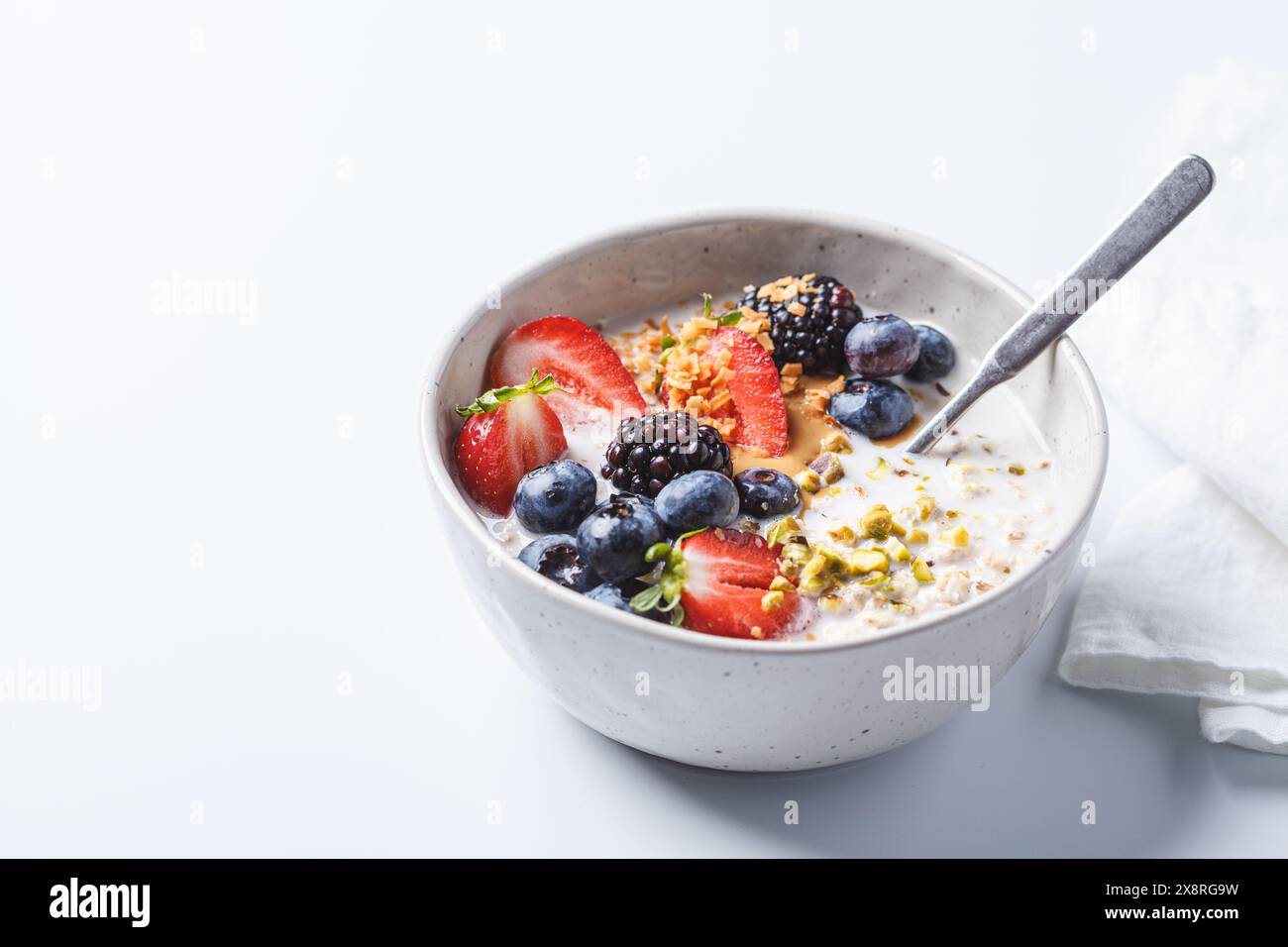Haferflocken über Nacht mit frischen Beeren und Nüssen, weißer Hintergrund. Gesundes Frühstückskonzept. Stockfoto
