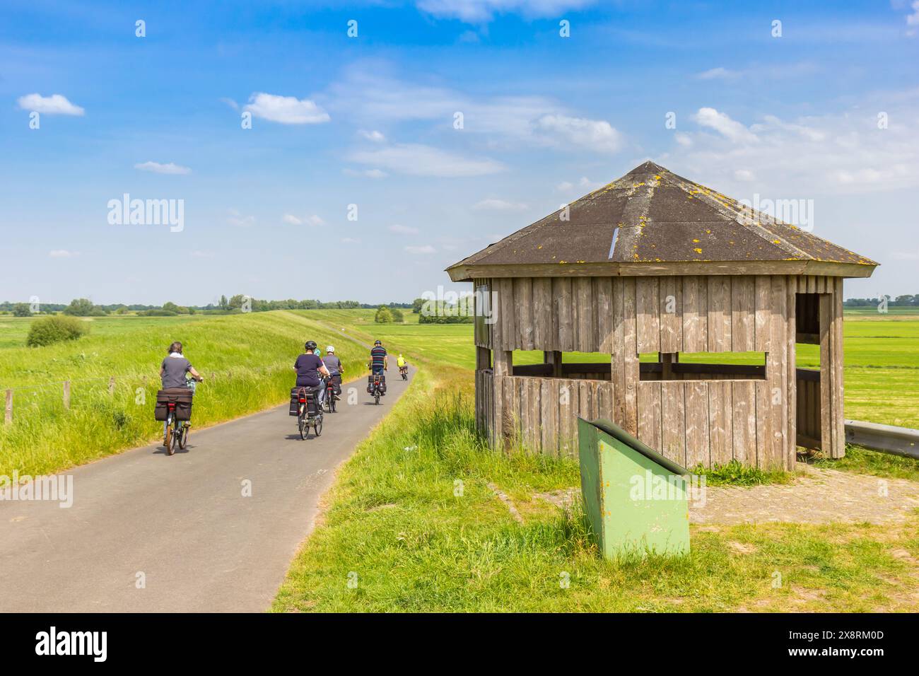 Radfahrer, die an einer Vogelhütte am Deich bei Papenburg vorbeifahren Stockfoto