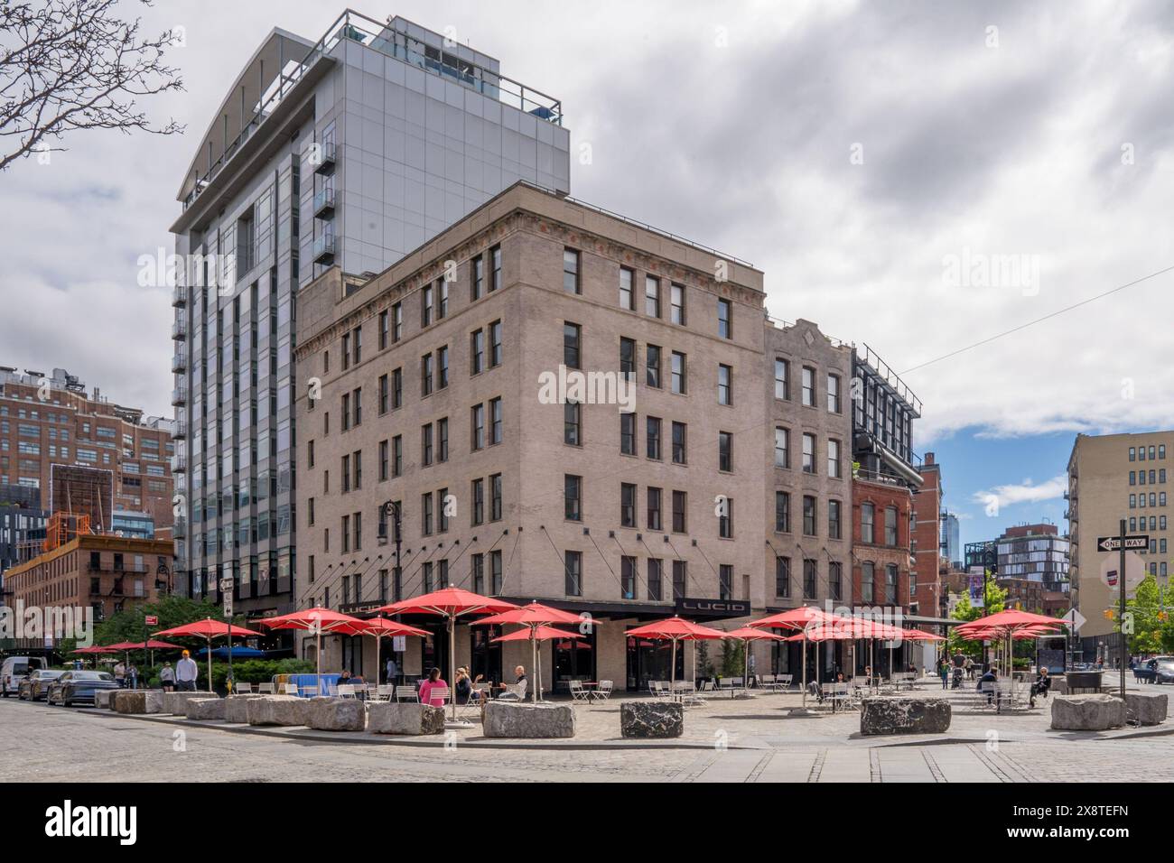 New York, NY - USA - 19. Mai 2024 Ein kopfsteingepflasterter platz mit roten Sonnenschirmen, Tischen und Stühlen im Meatpacking District, einem angesagten Geschäftsviertel auf dem f Stockfoto