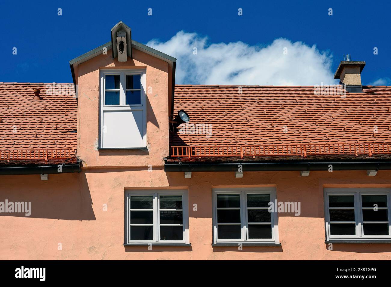 Rote Fassade und Ziegeldach mit Krandormer im Ensemble Mühlberg ist eine denkmalgeschützte Gruppe spätmittelalterlicher Häuser, Kempten, Allgäuer Stockfoto