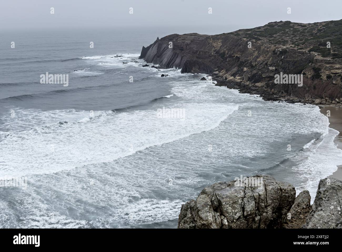 Malerischer Blick auf die zerklüfteten Klippen und den Atlantischen Ozean im Cabo San Vicente, Portugal. Die einzigartigen Felsformationen und die nebelige Atmosphäre schaffen einen Dramat Stockfoto
