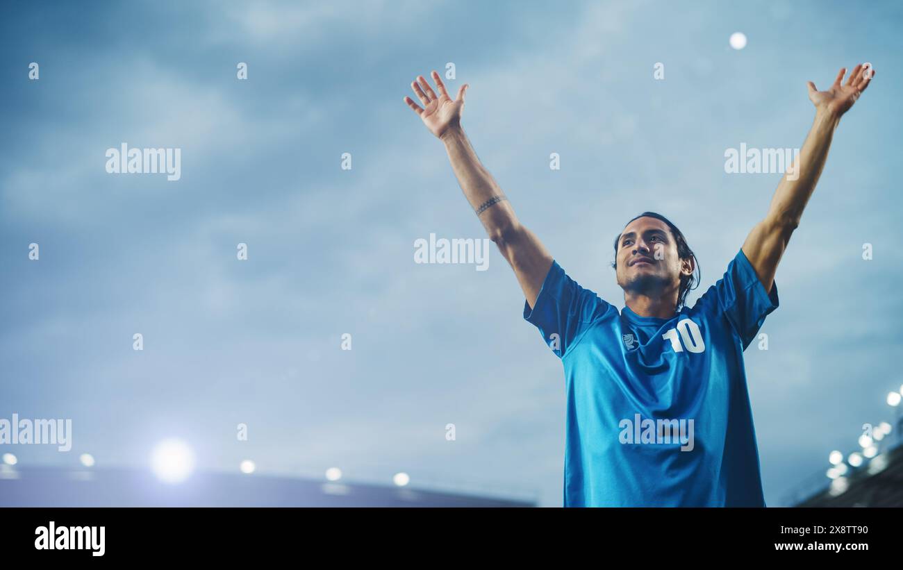 Football Match Championship: Porträt des Fußballspielers, der steht, posiert, lächelt, die Hände zum Anfeuern hebt. Professioneller hispanischer Fußballspieler, Champion Ready to Win Cup, Turnier. Mittlere Aufnahme Stockfoto