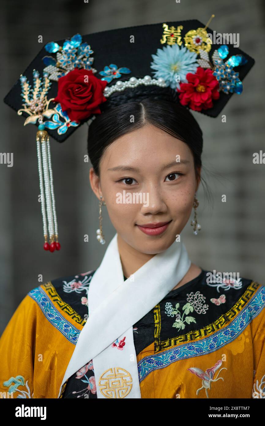 Zwei junge Frauen in leuchtenden gelben und blauen traditionellen Hofkostümen der Qing-Dynastie posieren im Freien in Peking, China. Stockfoto