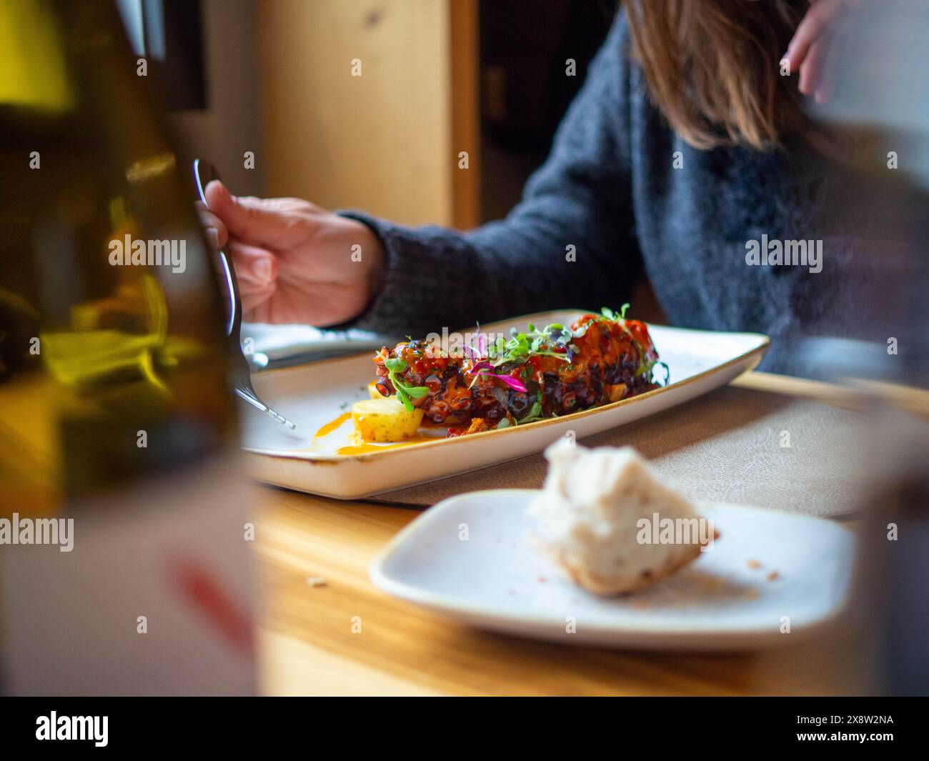 Detail einer jungen Frau in einem Restaurant, die Oktopus isst Stockfoto