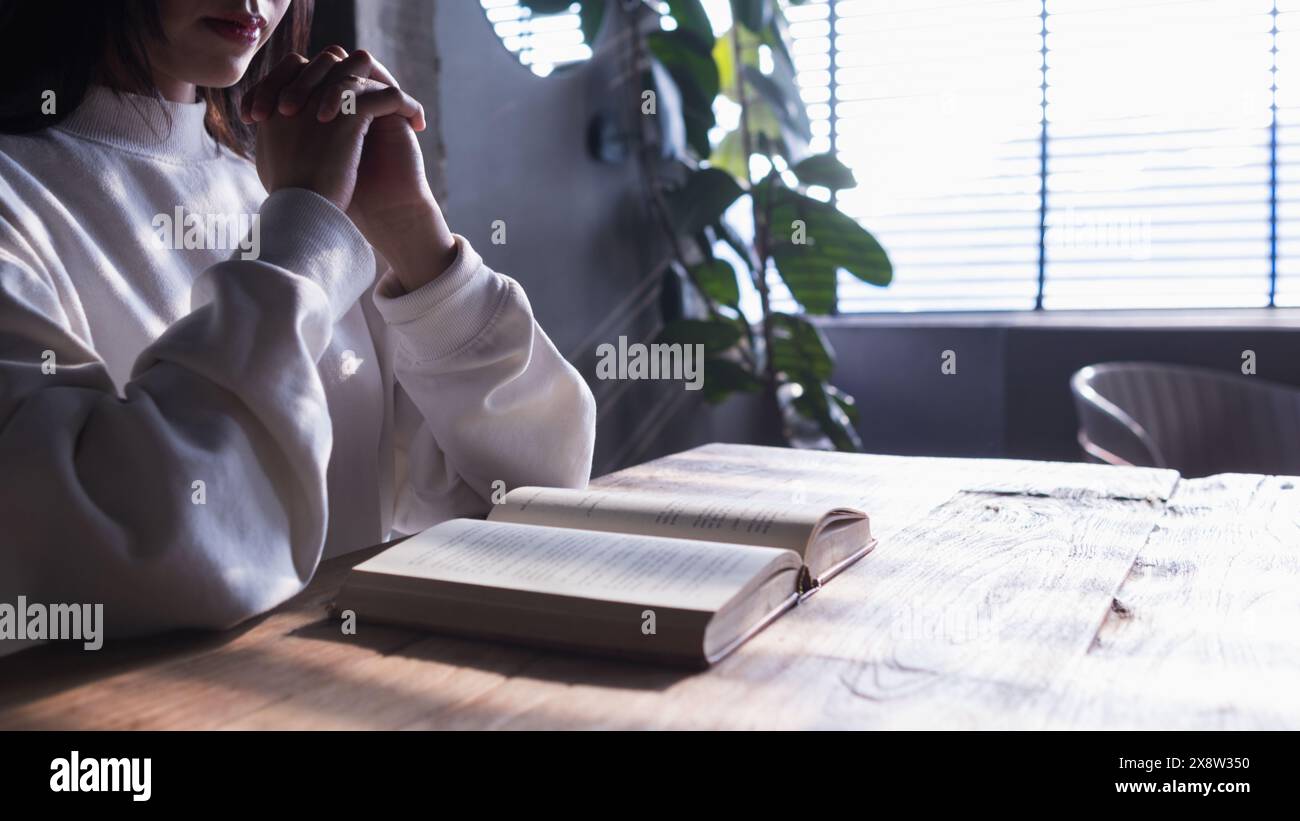 Die junge Frau hielt eine Bibel in der Hand und versuchte, Gottes Lehren aus der Bibel zu lernen und zu verstehen, die sie hielt. Glaubensbegriffe und die Macht von Stockfoto