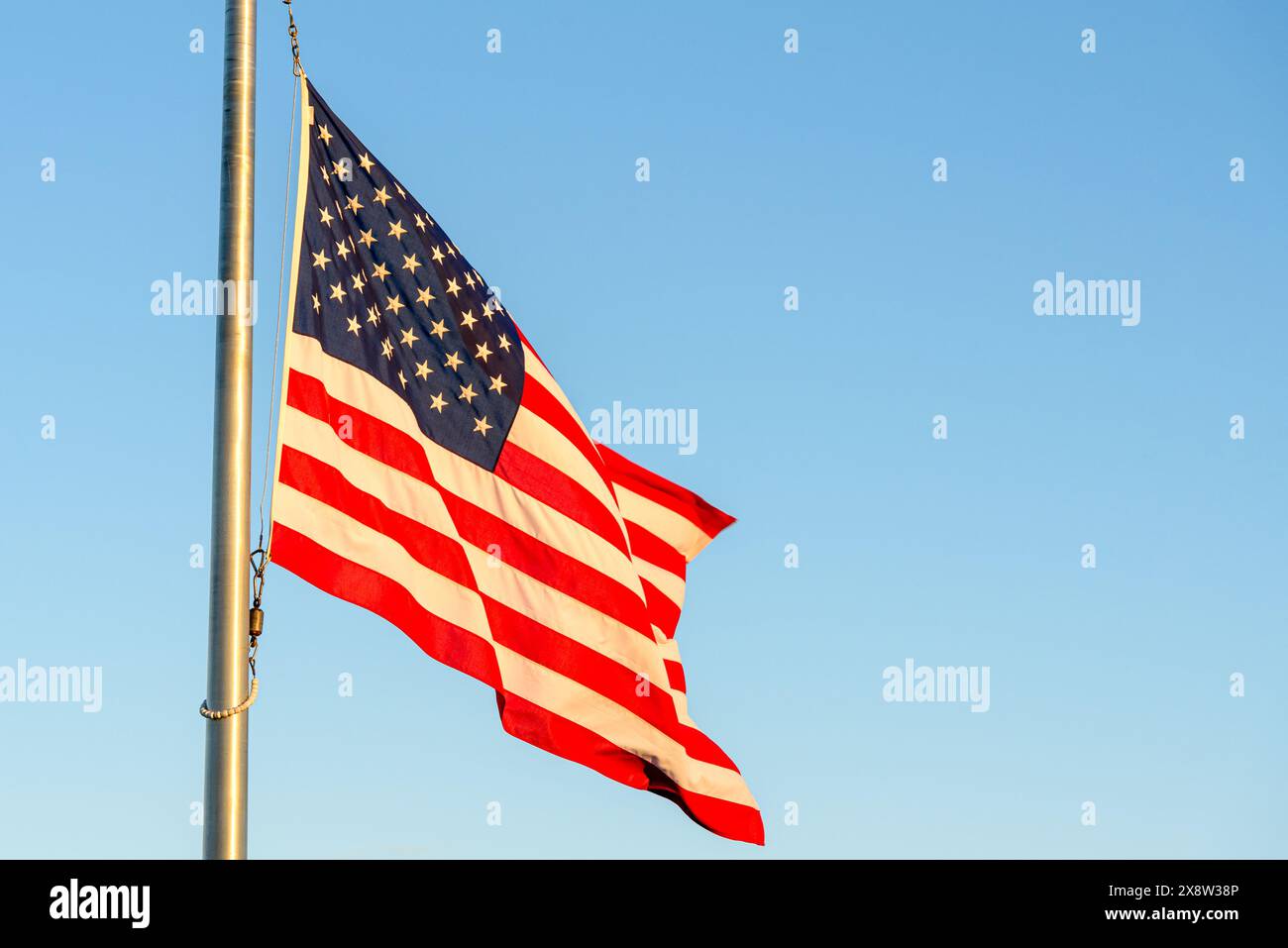 US-Nationalflagge winkt bei Sonnenuntergang gegen klaren Himmel. Kopierbereich. Stockfoto