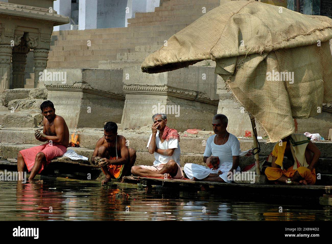 Benaras gilt als Kulturhauptstadt der ältesten und heiligsten Städte Indiens und Heimat der berühmtesten Ghats (150 Stufen, die zum Fluss führen) im Land. Riesige Massen von Pilgern und Besuchern aus allen Teilen der Welt versammeln sich, um an diesem alten Ritual teilzunehmen, bei dem es darum geht, der aufgehenden Sonne Opfergaben (Puja) zu machen. Benaras ist ein traditionelles Zentrum des Lernens von Philosophie, Sanskrit, Astrologie und Religion. Benaras, Uttar Pradesh, Indien. Stockfoto