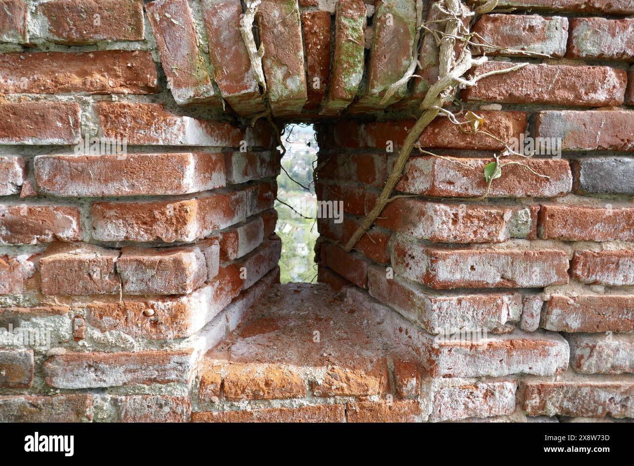 Pfeilschlitzfenster in der alten Ziegelsteinmauer Stockfoto