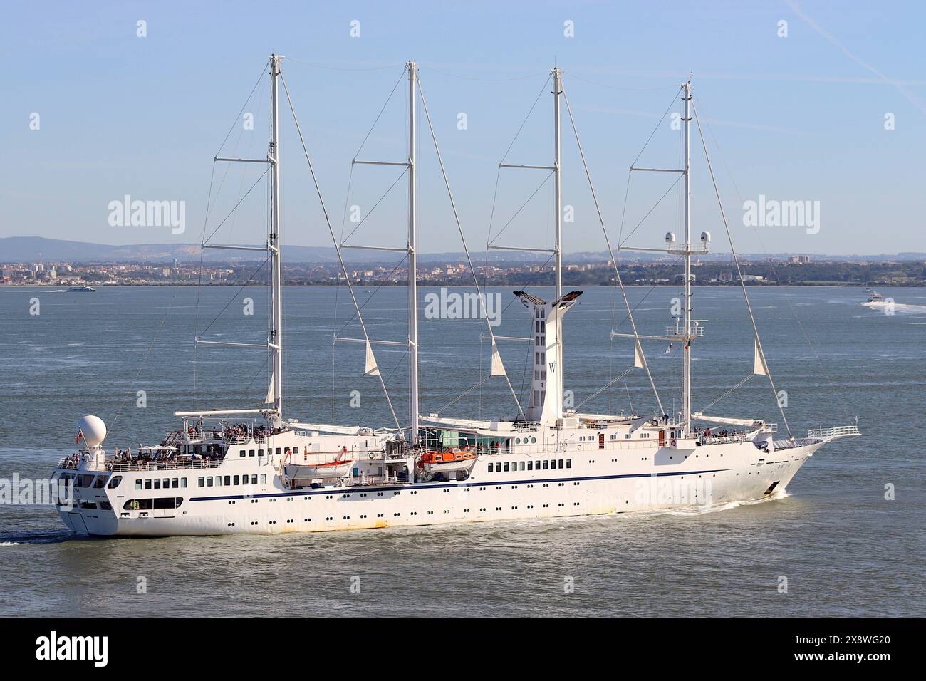 Die Windstar Luxury Kreuzfahrtschoner rutscht ihre Anlegestellen und segelt den Fluss Tejo hinunter, um wieder auf das offene Meer zu fahren, um ihre geplante Kreuzfahrt fortzusetzen. Stockfoto