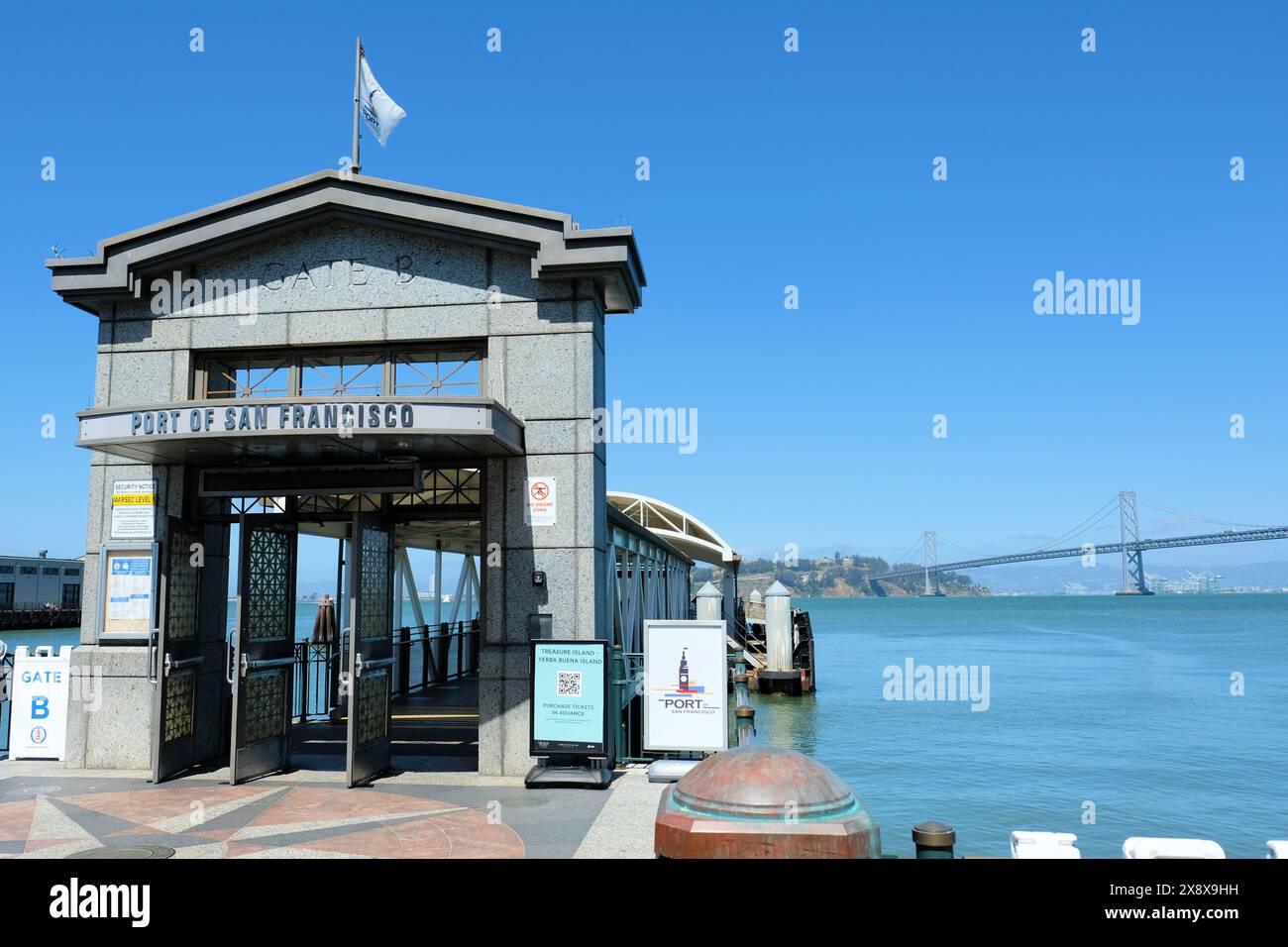 San Francisco Ferry Building Gate B Docking Station für Fähren nach Marin County und Treasure Island mit Bay Bridge im Hintergrund. Stockfoto