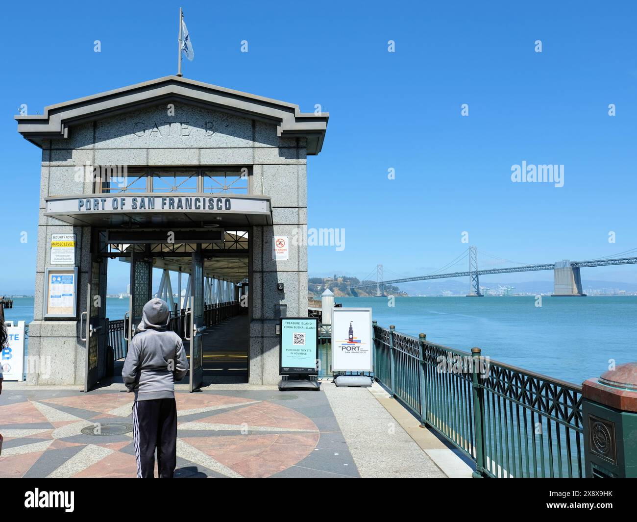 San Francisco Ferry Building Gate B Docking Station für Fähren nach Marin County und Treasure Island mit Bay Bridge im Hintergrund. Stockfoto