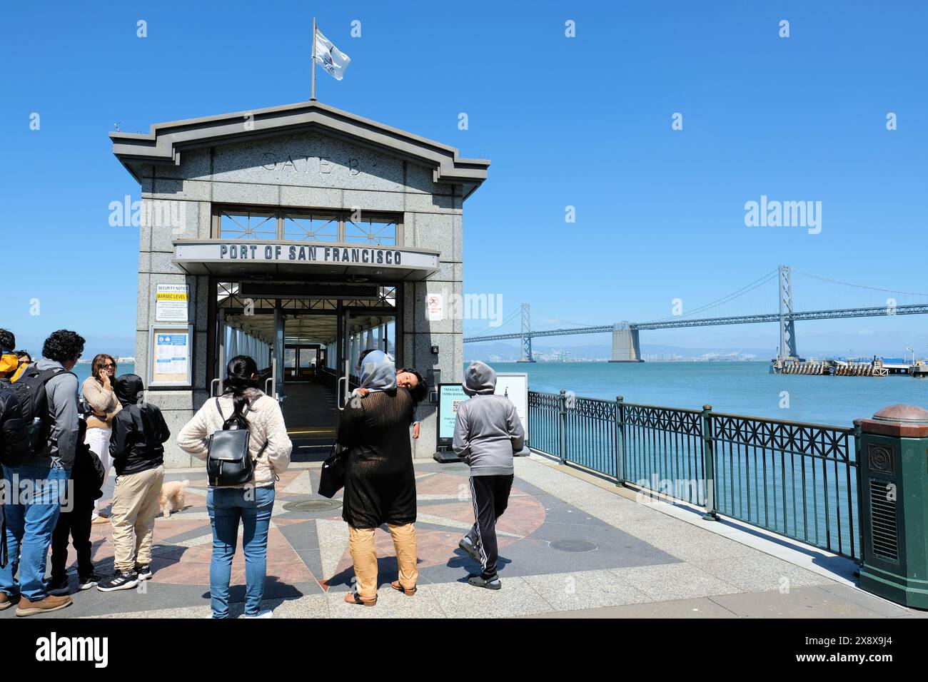 Passagiere an der Andockstation des San Francisco Ferry Building Gate B für Fähren nach Marin County und Treasure Island mit Bay Bridge im Hintergrund. Stockfoto