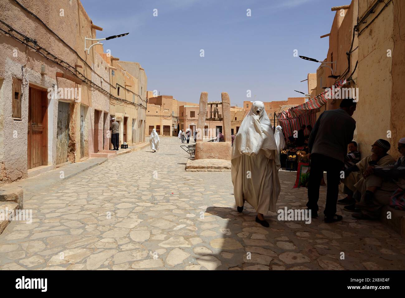 Verhüllte mozabittische Frauen in weißem haik auf dem Marktplatz von Ksar Beni Isguen. Beni Isguen ist eine der 5 Ksars (befestigte Siedlung) im Mzab-Tal. Provinz Ghardaia. Nord-Sahara. Algerien Stockfoto