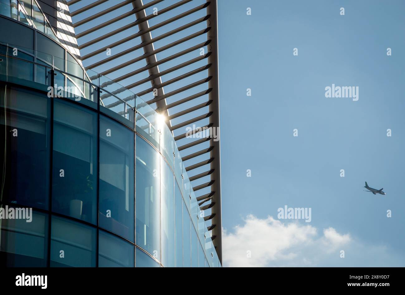 Zeitgenössische Architektur in London mit elegantem Glas- und Stahldesign, mit einem Flugzeug im Hintergrund. Perfekt für Architekturliebhaber. Stockfoto